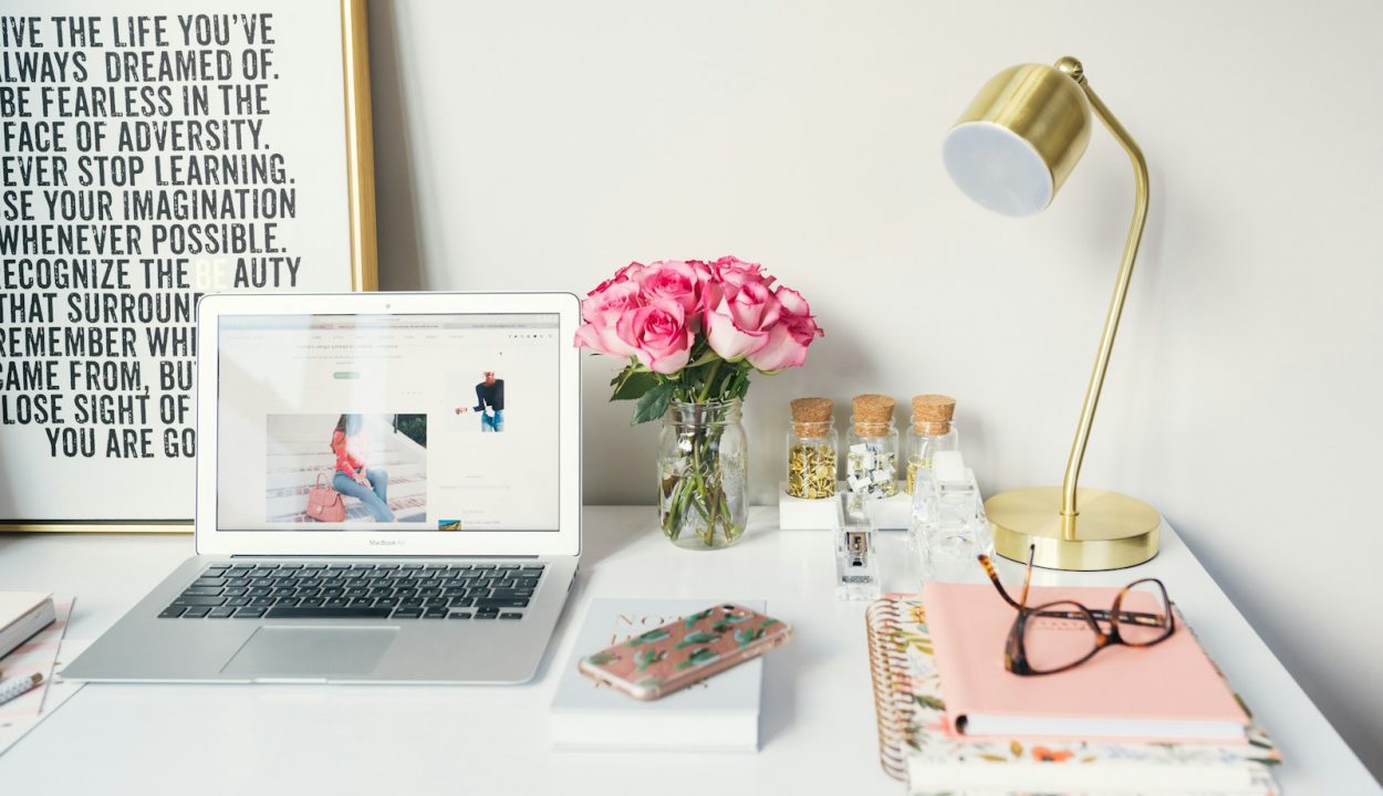 MacBook Air beside gold-colored study lamp and spiral books