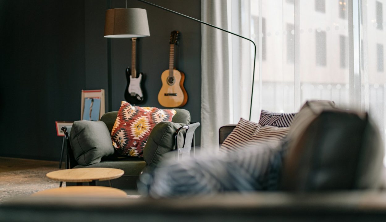 a living room filled with furniture and a guitar on the wall